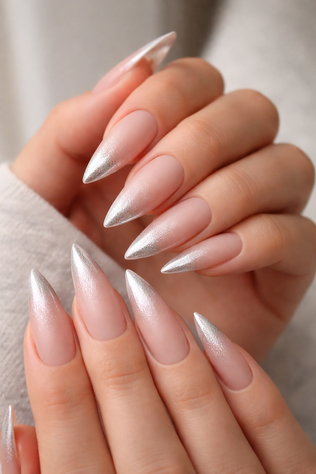 Close-up of frosted nude stiletto nails with a subtle metallic gradient at the tips