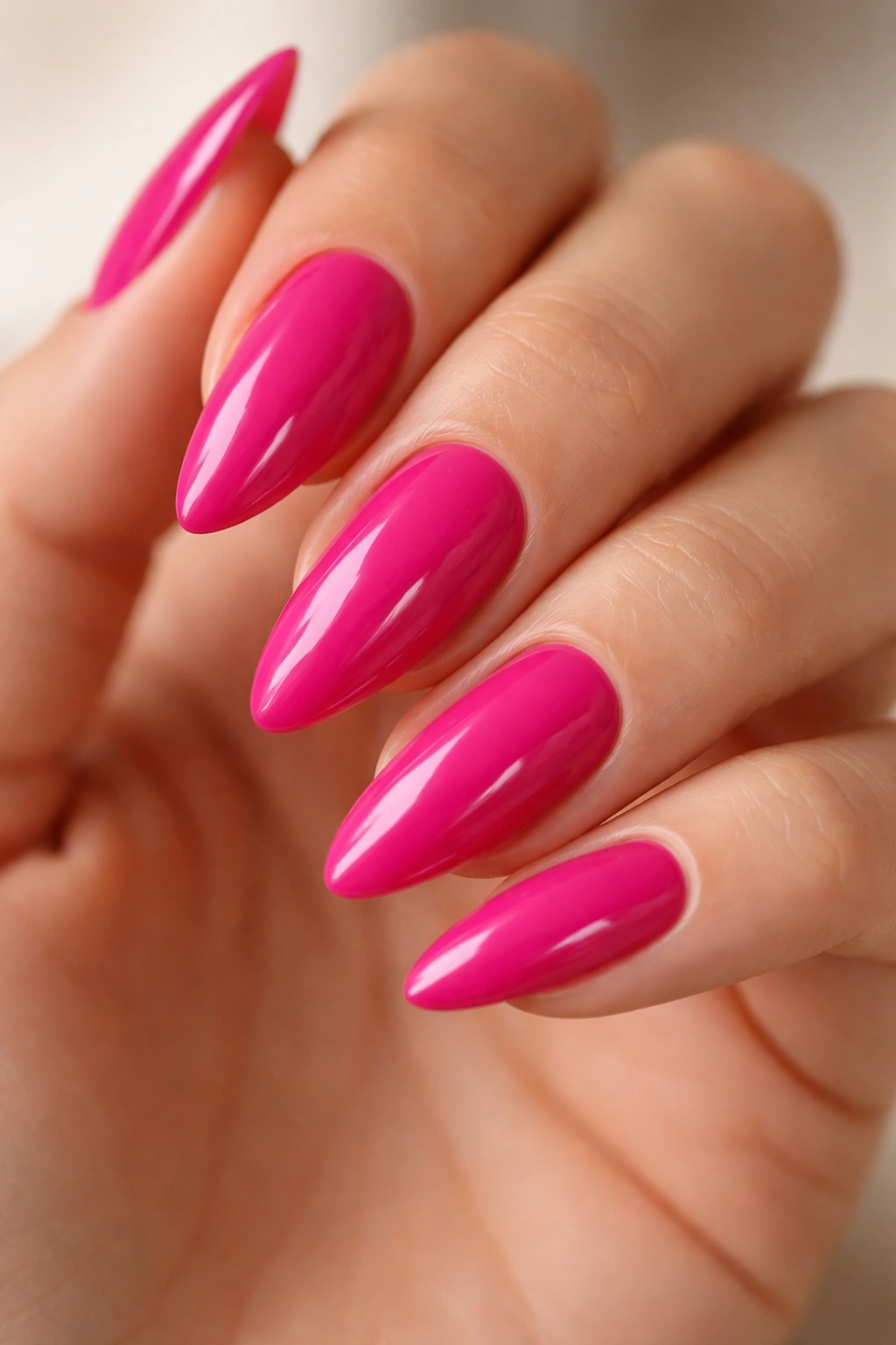 Close-up of bright fuchsia almond nails with glossy lacquer