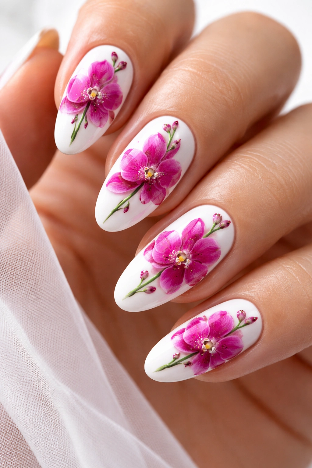 Close-up of short almond nails with bright fuchsia orchid blooms on a glossy white base.