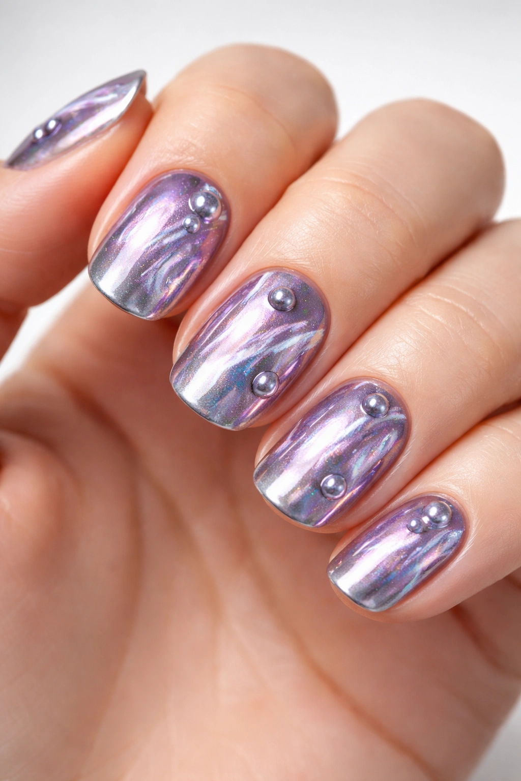 Close-up of metallic galaxy chrome nails with silver-lilac swirls and 3D bubbles