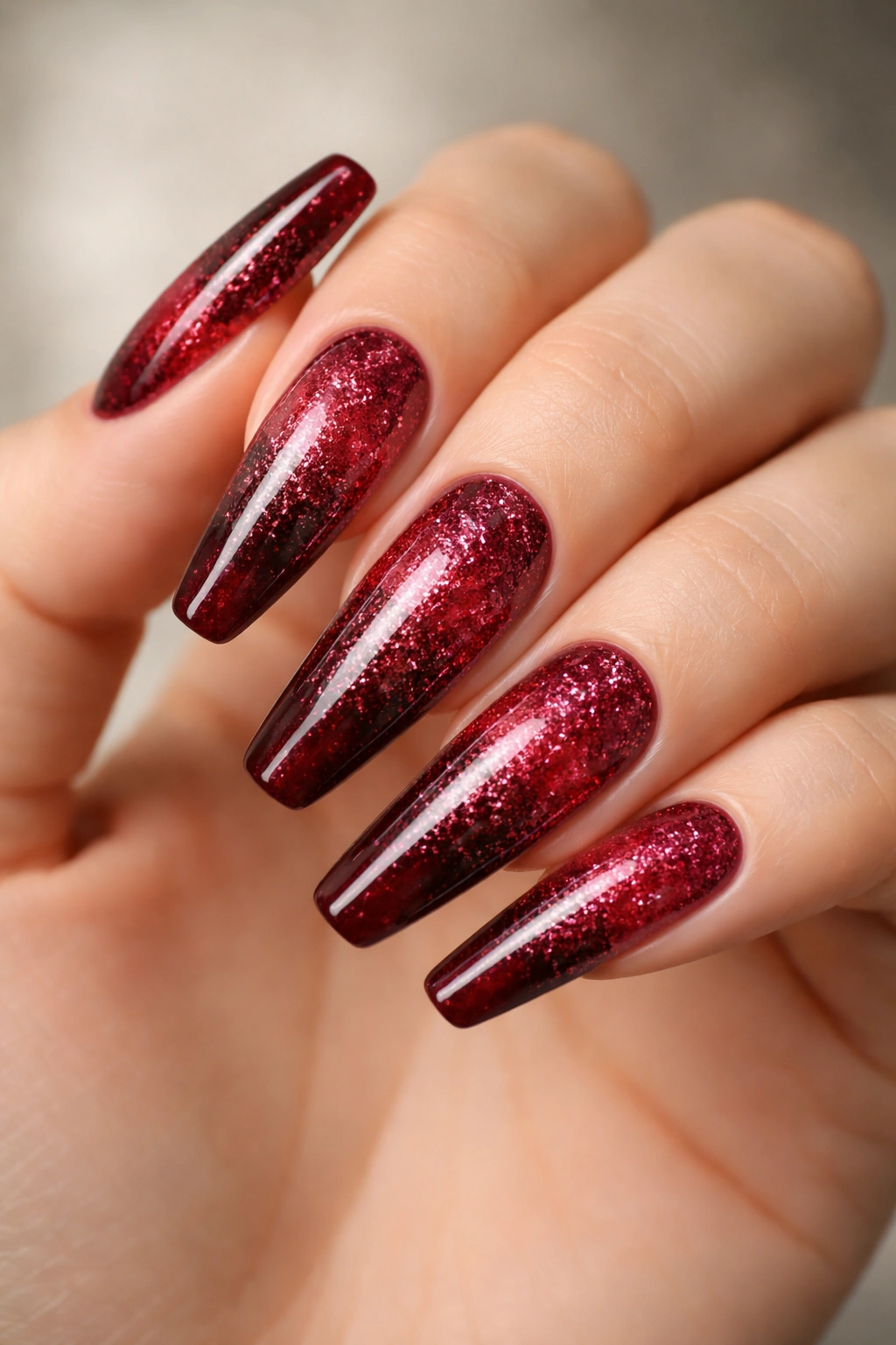 Garnet glitter ombre nails on long ballerina tips with glassy finish.