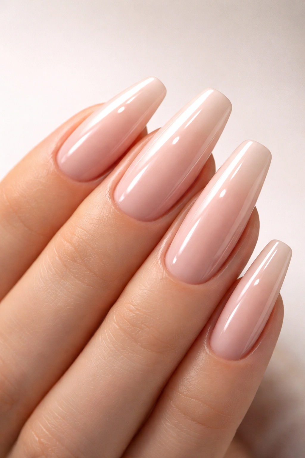 Close-up of a hand with shiny gel nails under soft studio light