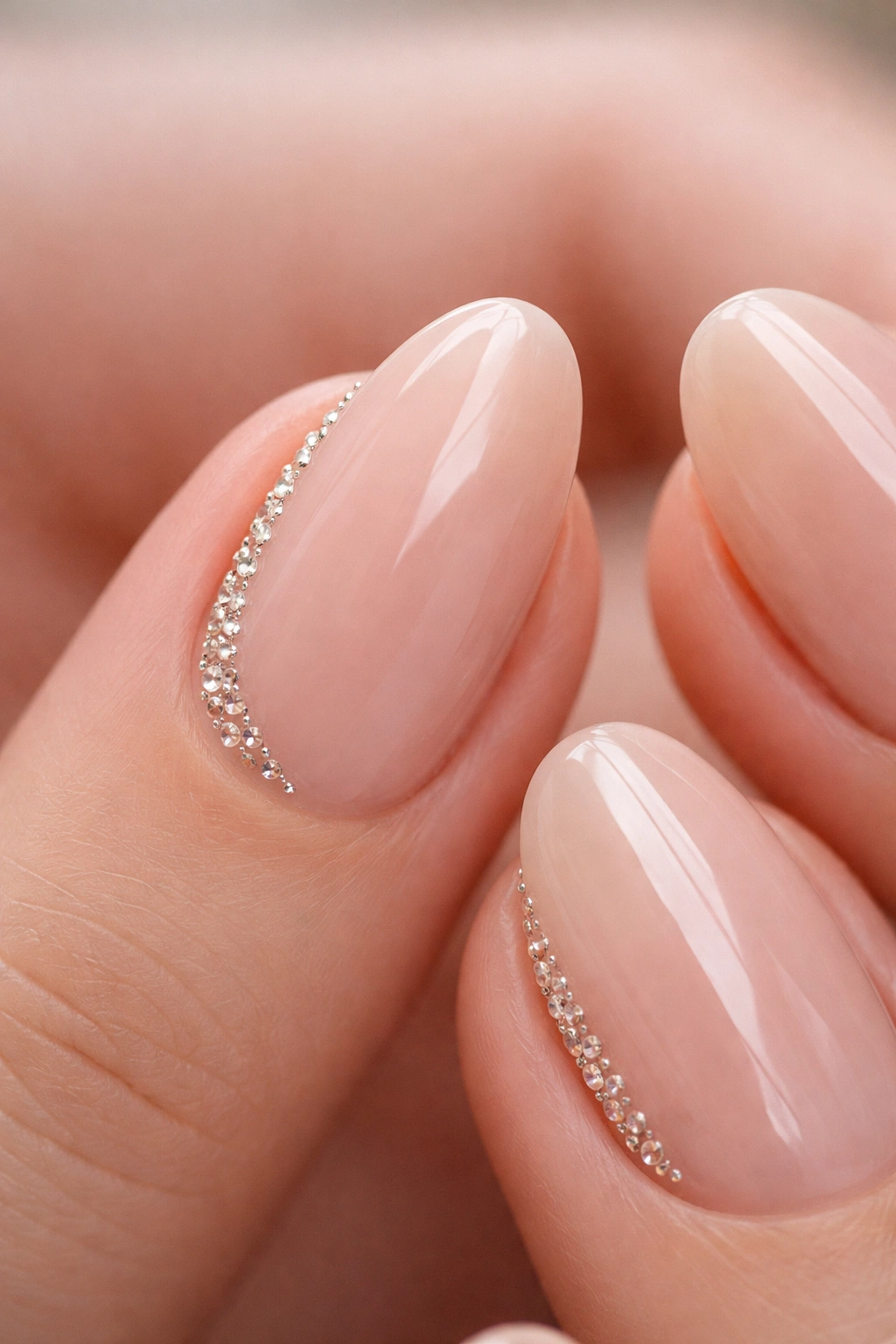 Close-up of a short almond nail with a slim line of crystals along the side near the cuticle