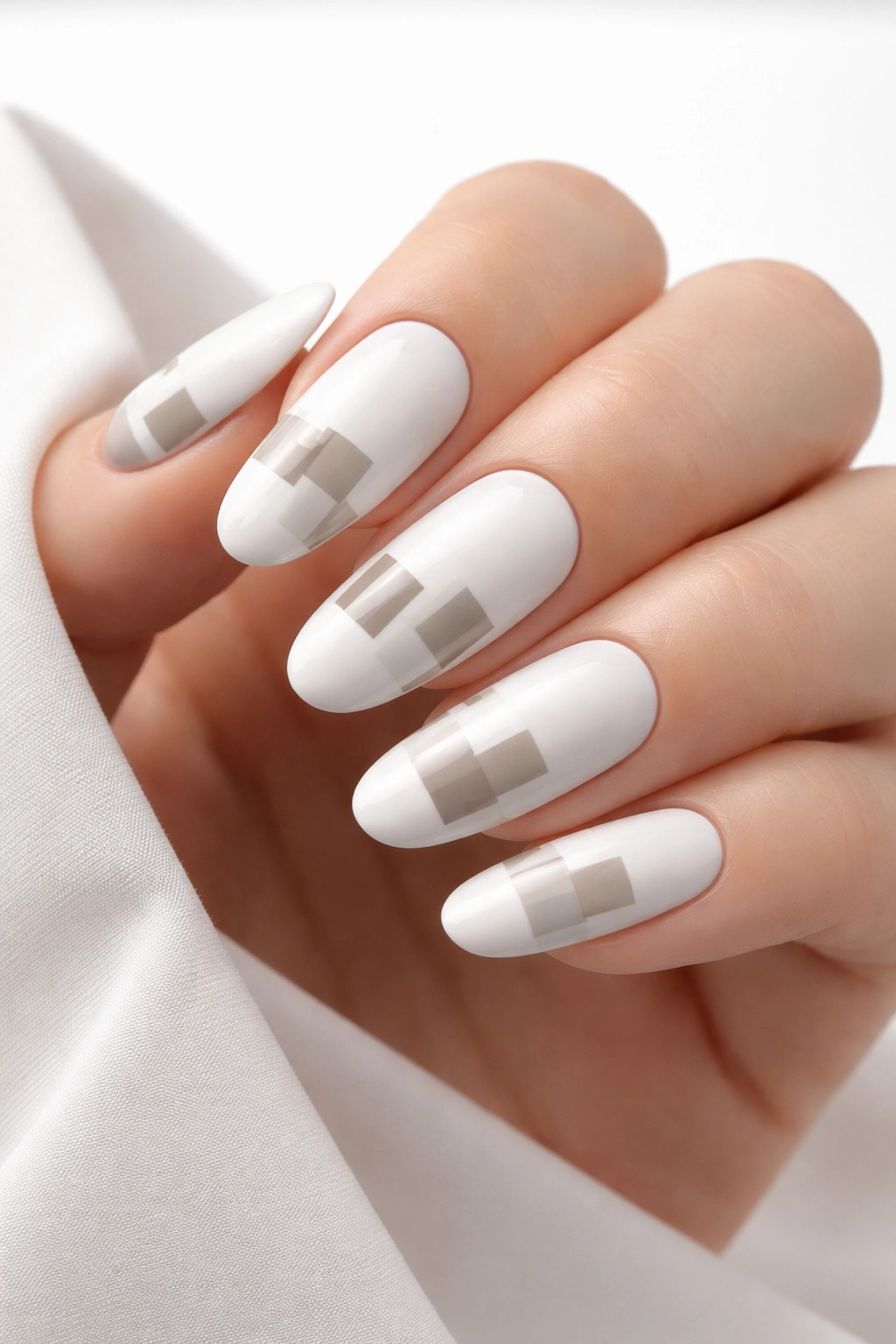 Close-up of long oval nails with geometric color blocks on white base