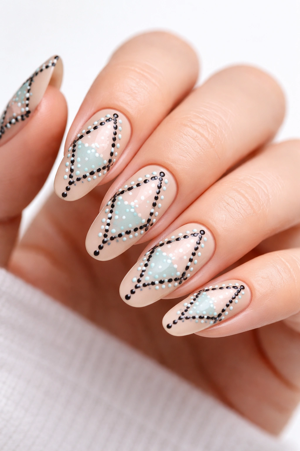 Close-up of long round nails with nude base and geometric dot outlines