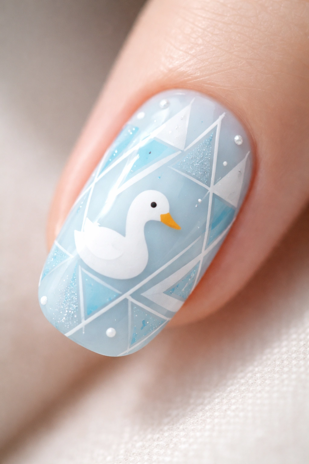 Nail art with baby blue base, geometric shapes, and a white duck silhouette