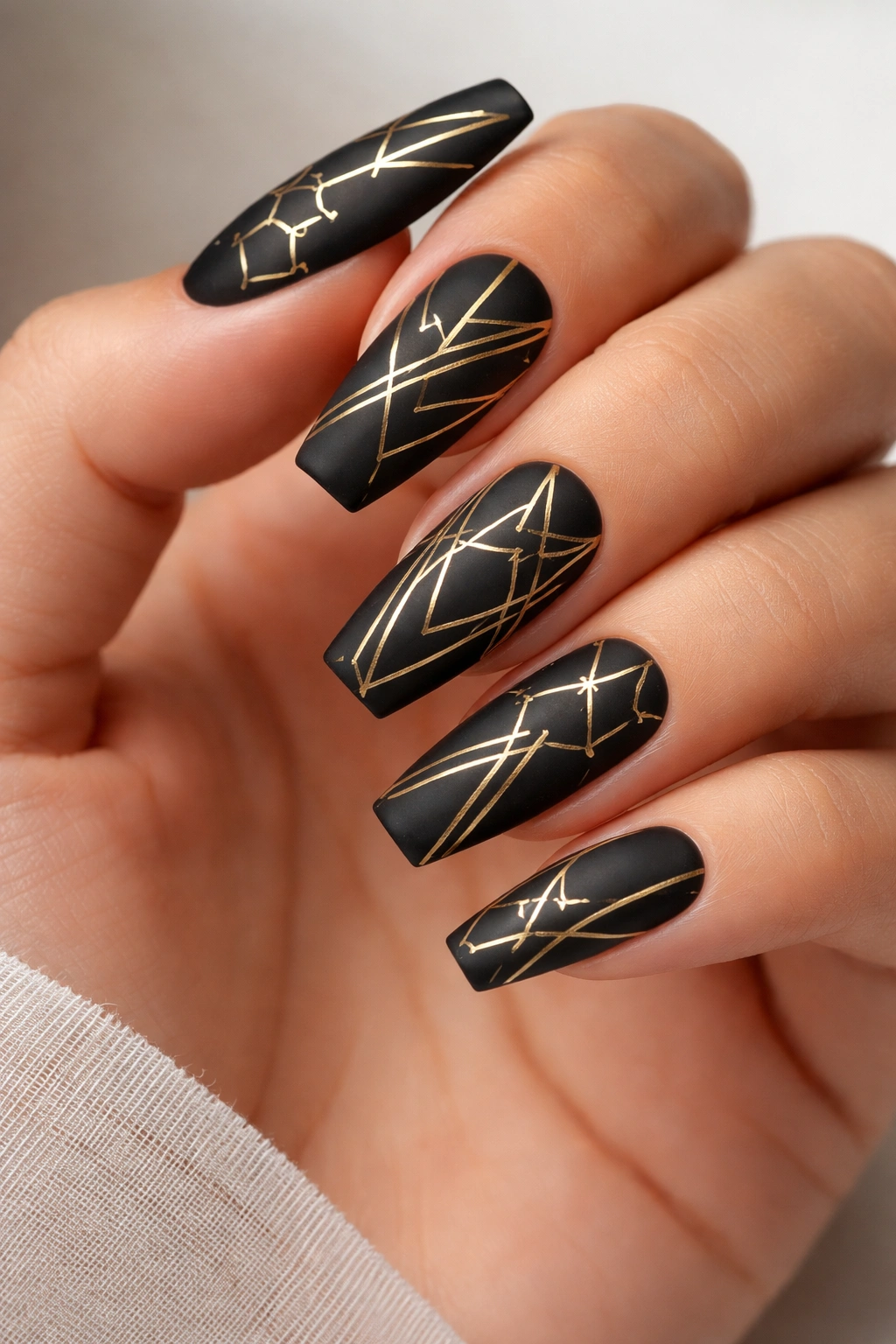 Coffin nails with matte black base and gold geometric patterns