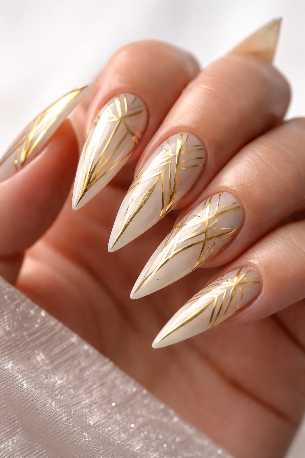 Geometric gold pattern nails with clean lines on stiletto tips