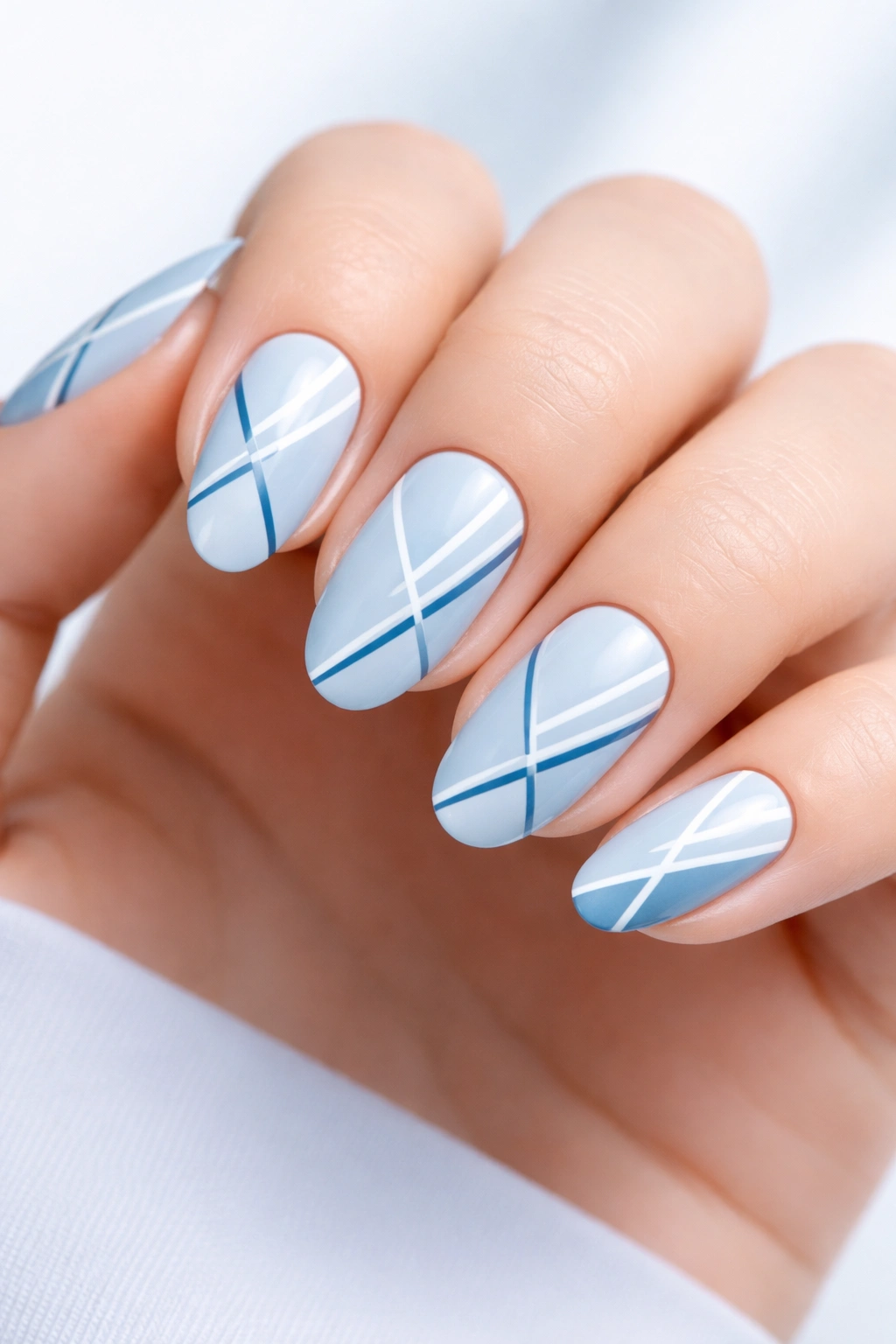 Nails with light blue base and white and dark blue geometric lines
