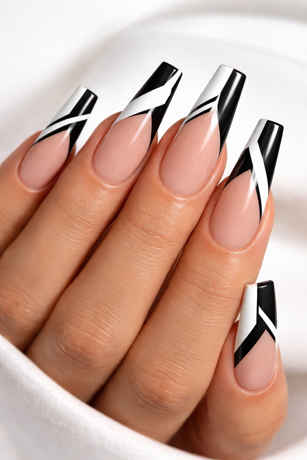 Close-up of long coffin nails with black geometric tip designs on nude base