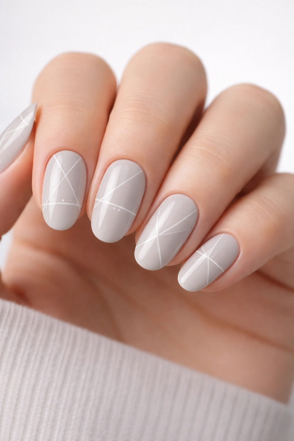 Close-up of nails with neutral base and minimalist geometric line patterns