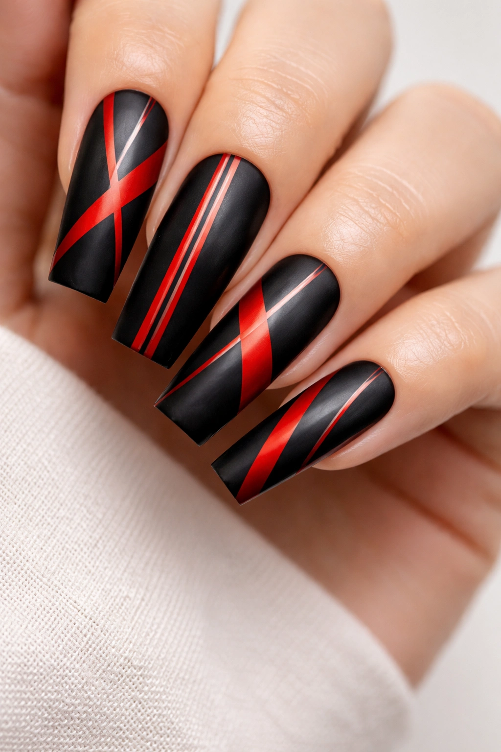 Close-up of coffin nails with geometric red stripes on black base
