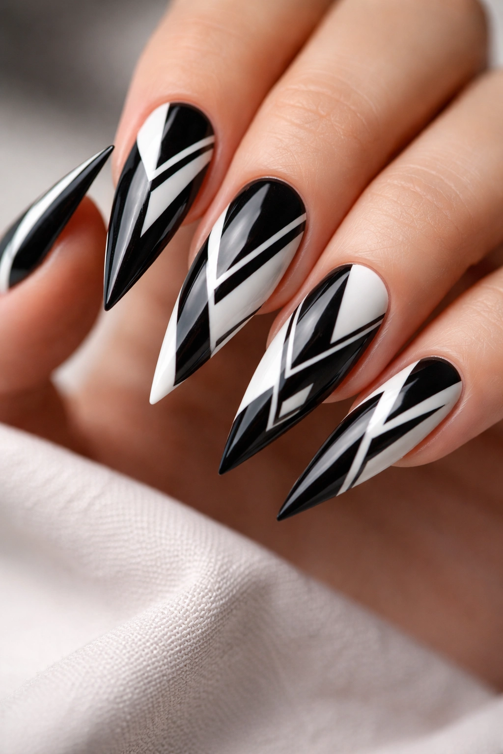 Close-up of stiletto nails with black and white geometric triangles