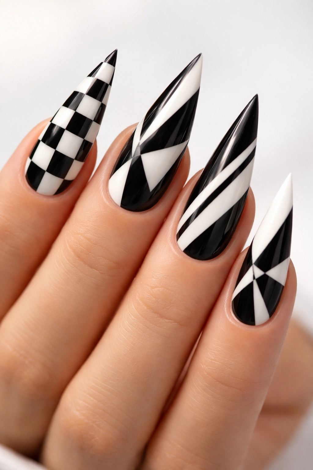 Stiletto nails with crisp black and white geometric patterns on a light background
