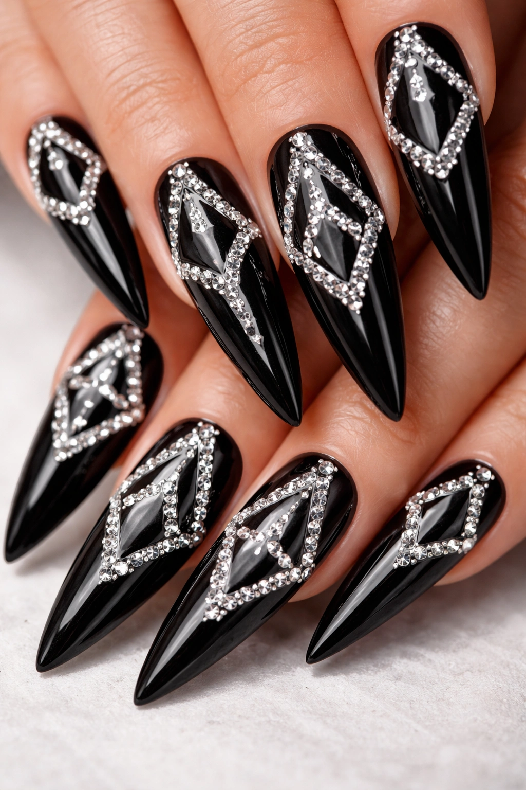 Black stiletto nails with geometric rhinestone patterns