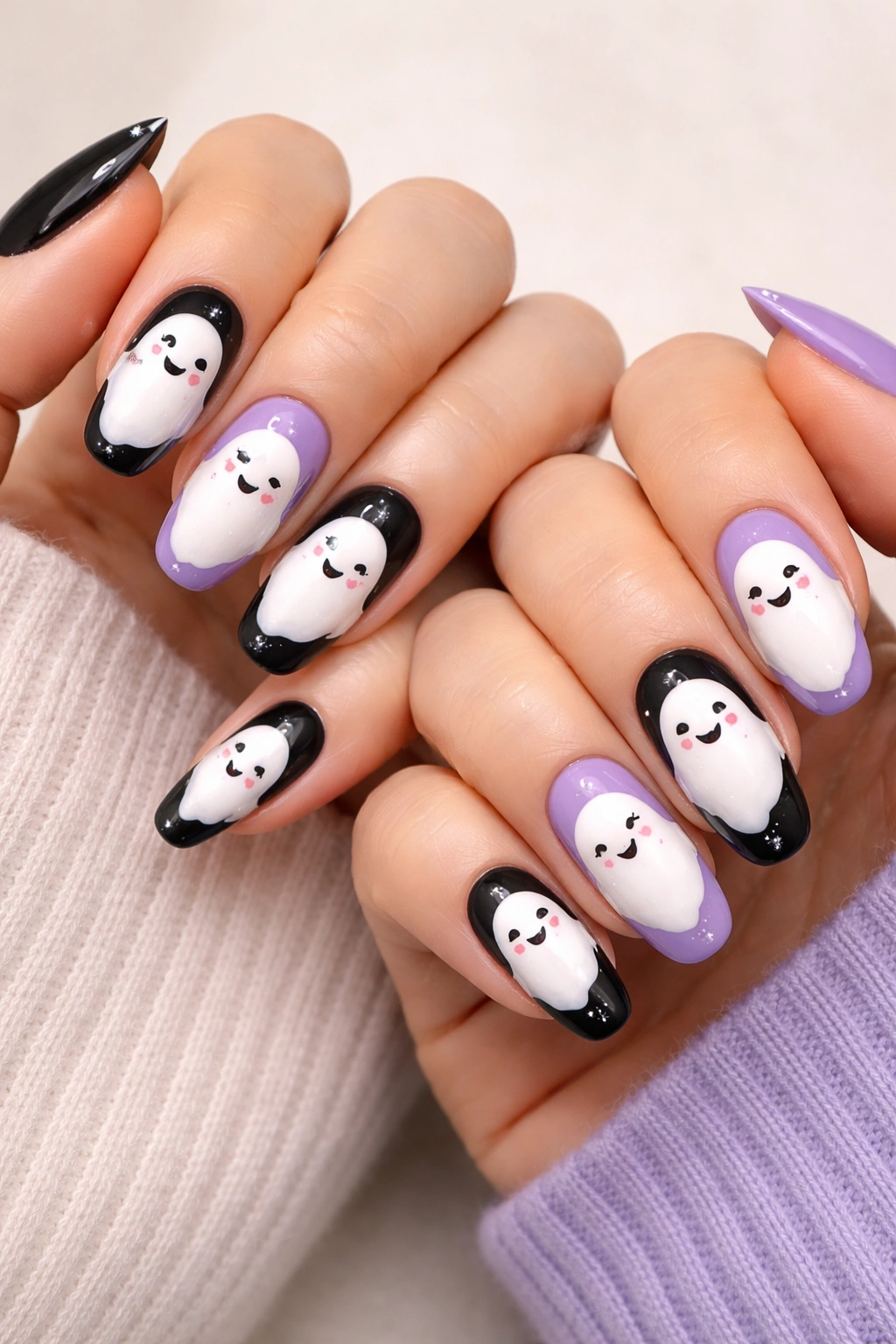Two hands with matching ghost nail art on varied bases in Halloween colors