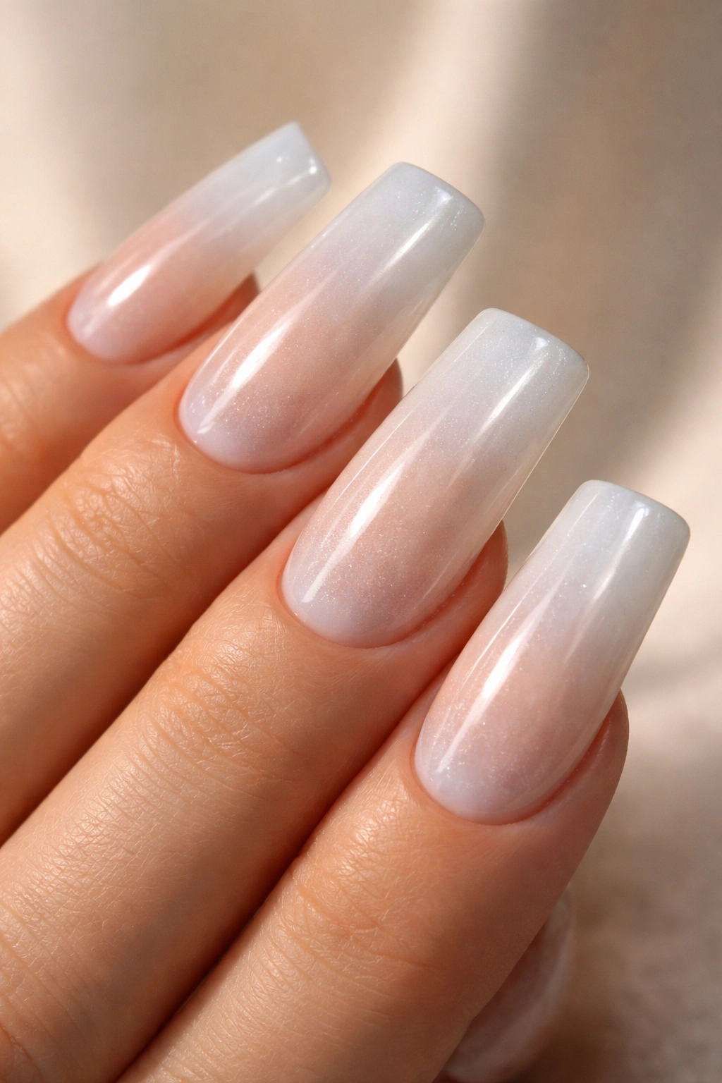 Hand with milky white duck nails featuring glazed donut gradient