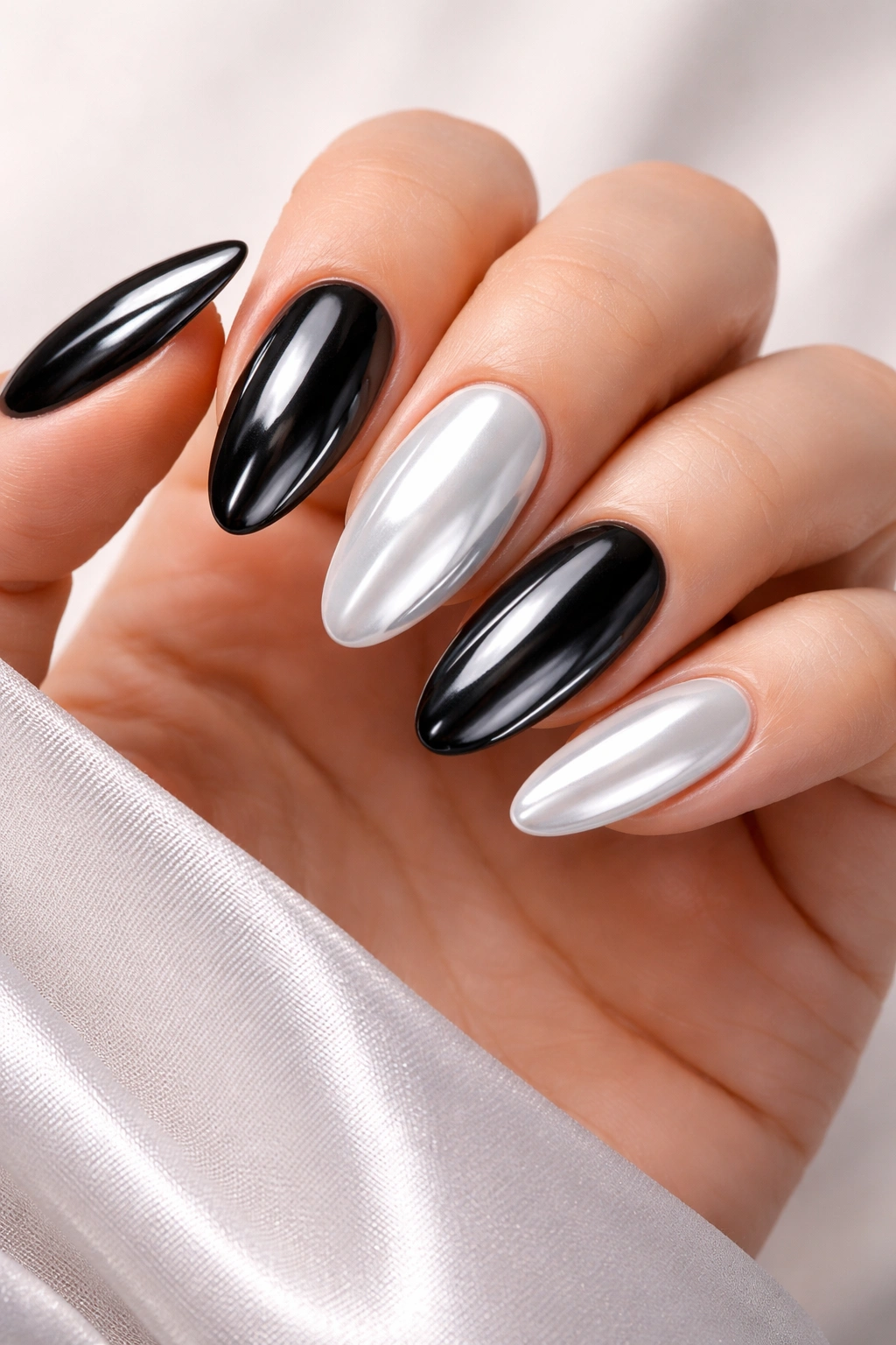 Close-up of glazed black and white skittle nails on a hand with pearly chrome finish