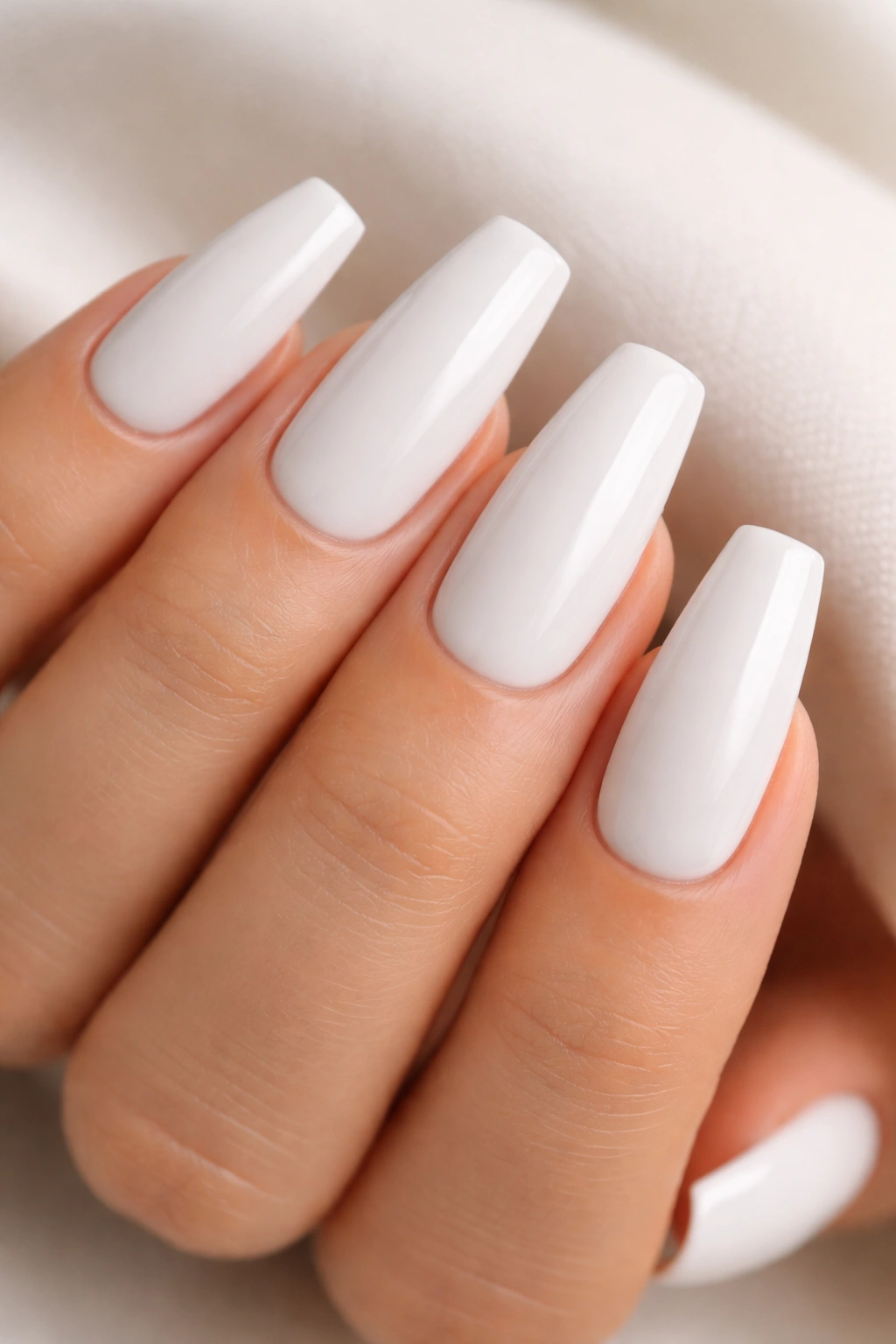 Close-up of medium coffin nails with glazed white polish and soft shine