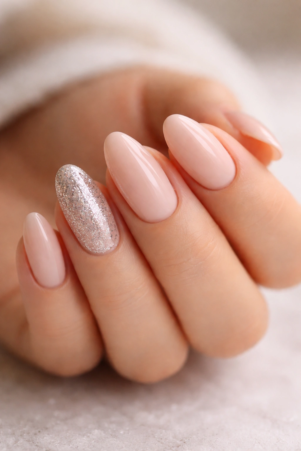 Close-up of glitter accent almond nails on short nails with subtle sparkle