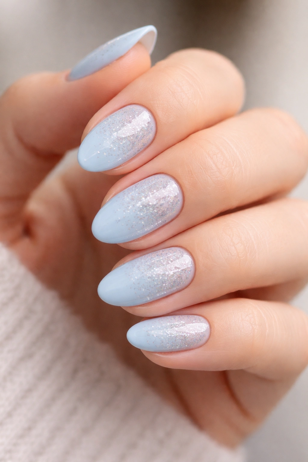 Close-up of soft blue nails with subtle glitter fade on short almond nails