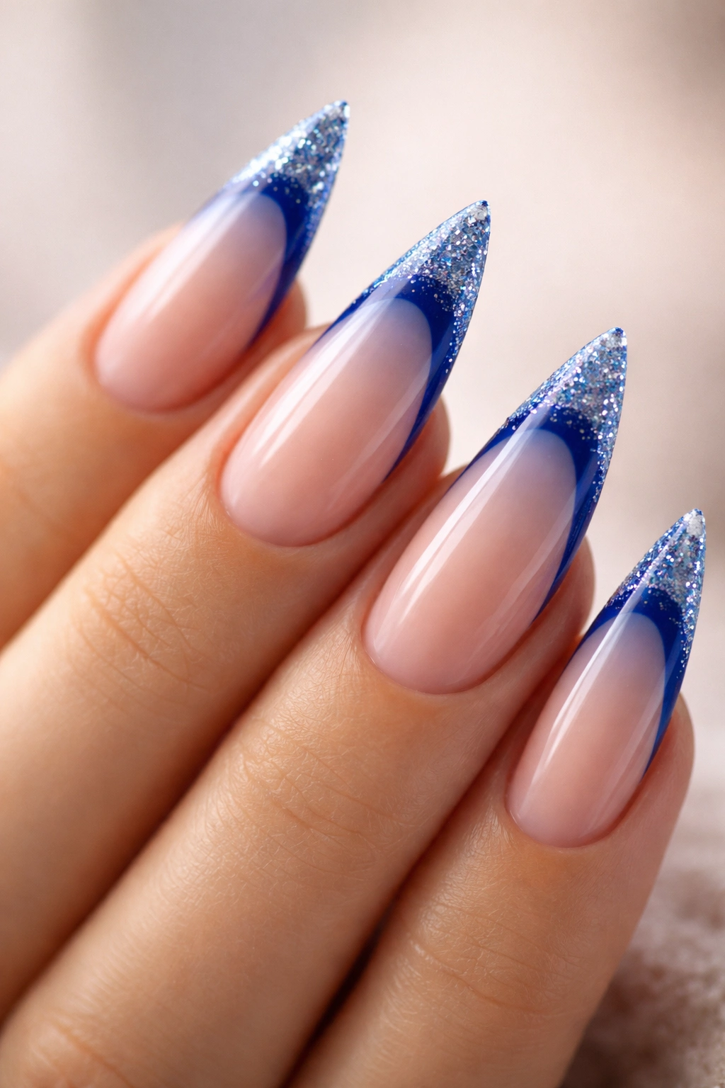 Close-up of glitter-dipped blue French tip nails on stiletto shape