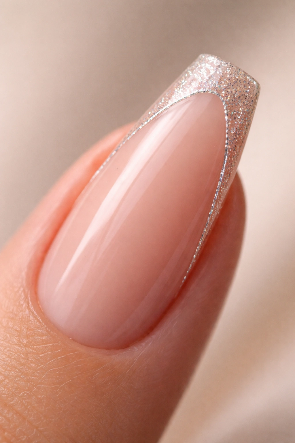 Close-up of a curved coffin nail with a nude base and glitter line along the tip