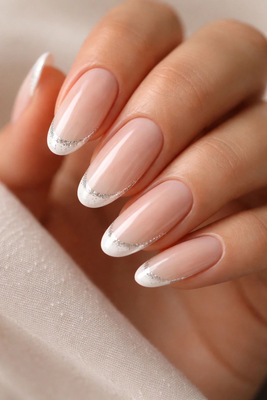 Close-up of long oval nails with glitter-edged tips on a nude base