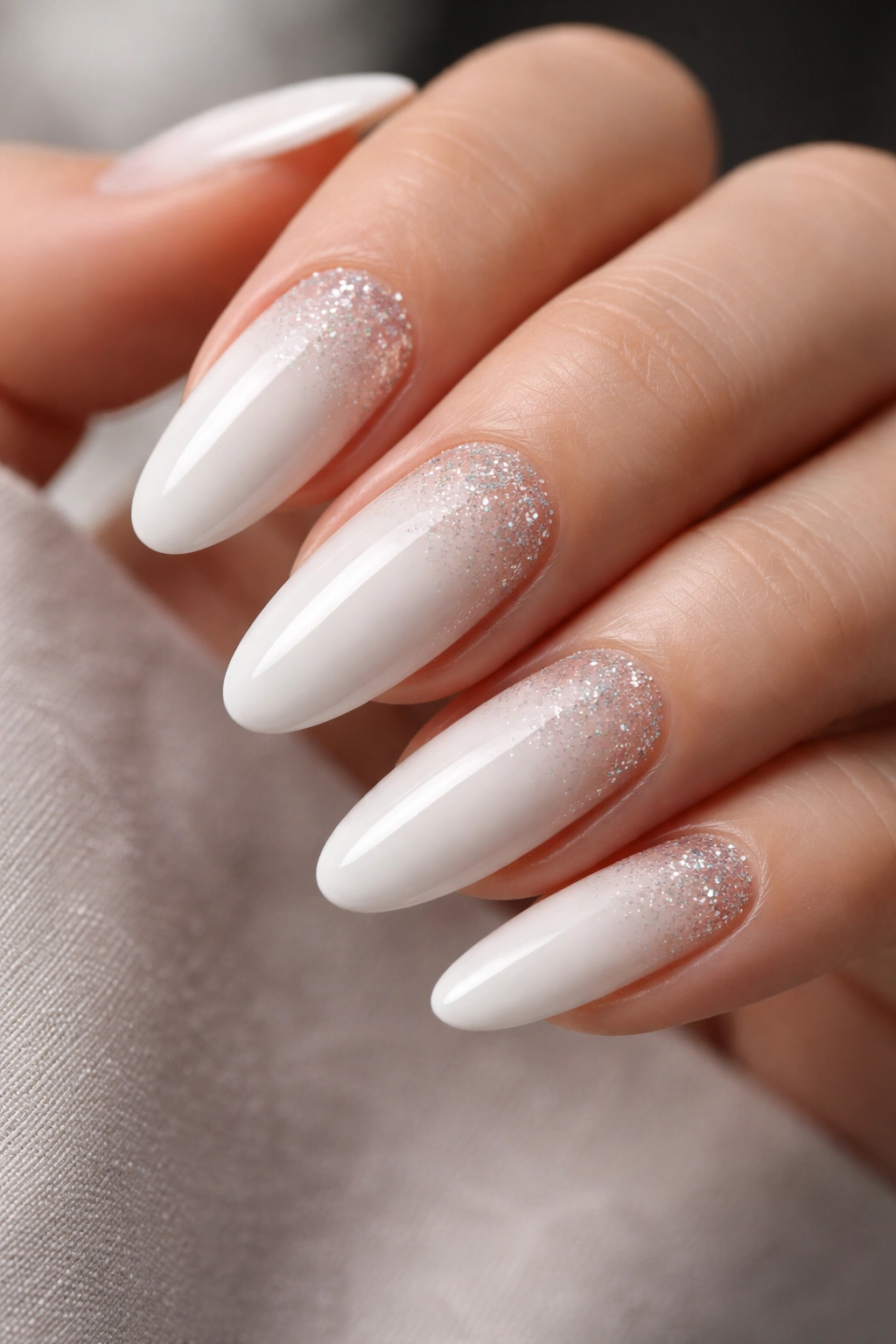 Close-up of white long oval nails with a subtle glitter fade