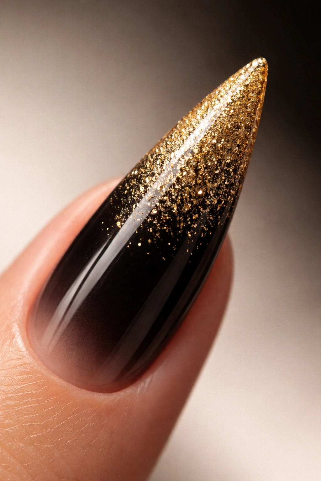 Stiletto nail with gold glitter gradient fading into black
