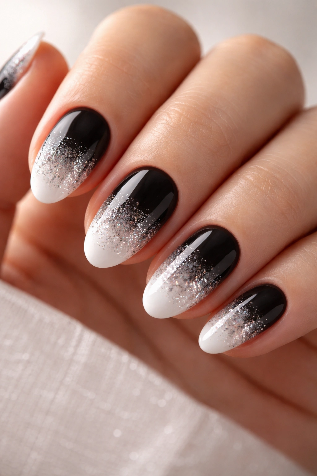 Glitter gradient on the white tip of short almond nails with subtle sparkle.
