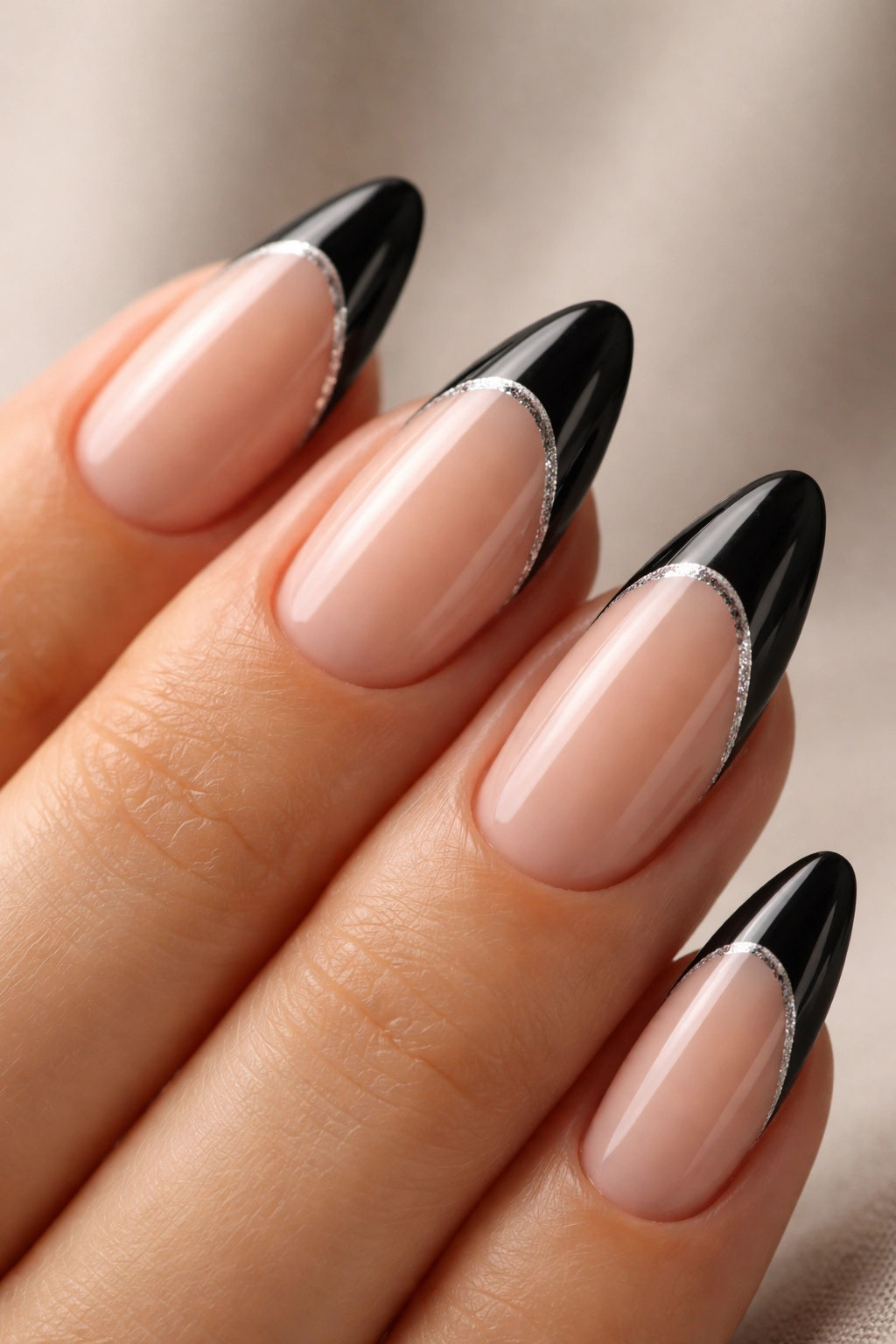 Almond nails with glitter-lined black french tips on nude base