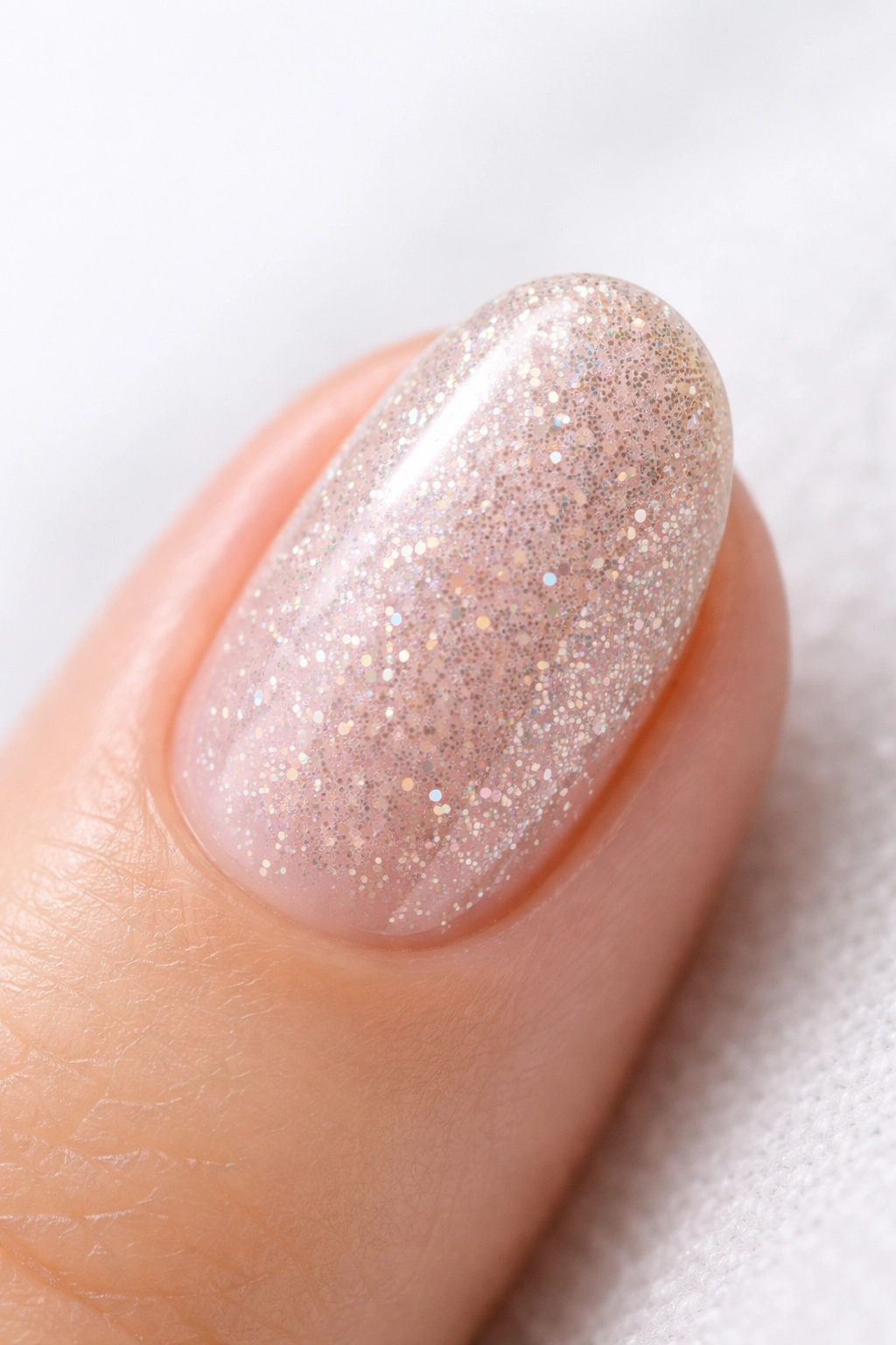 Close-up of a neat, glossy glitter nail on a short oval shape