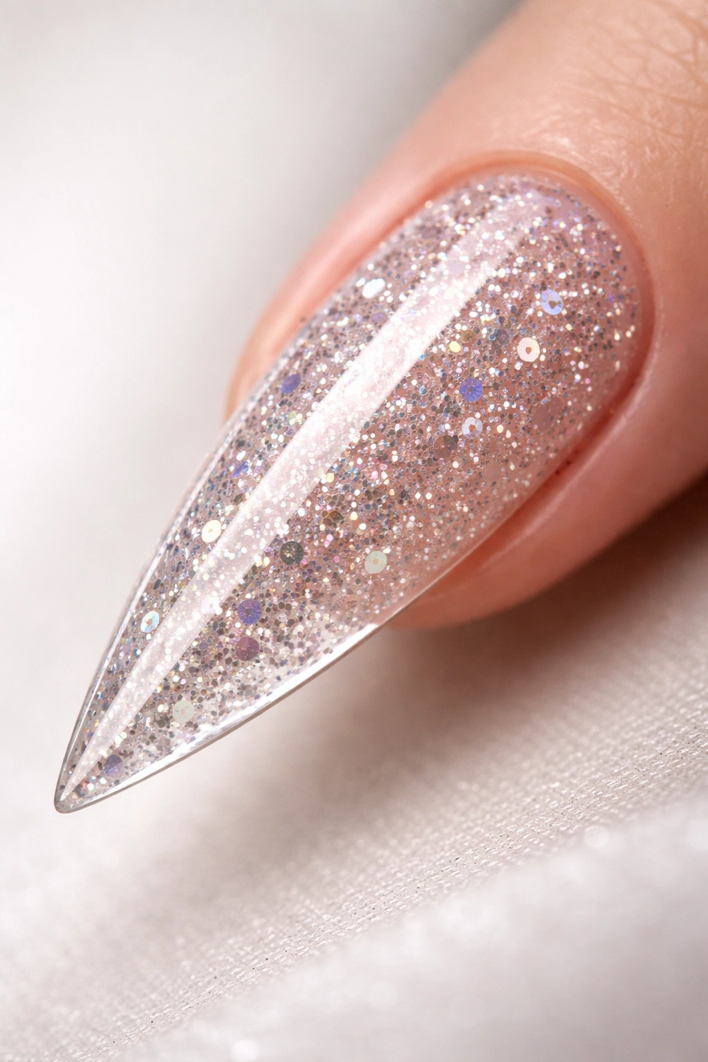 Close-up of a stiletto nail with glitter sealed under a clear topcoat