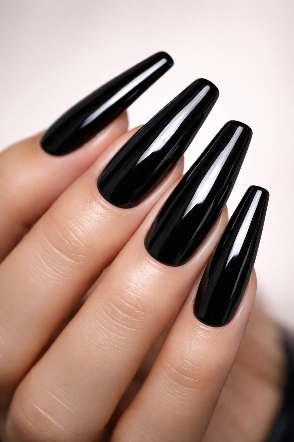 Close-up of glossy black coffin nails with a mirror finish on a hand