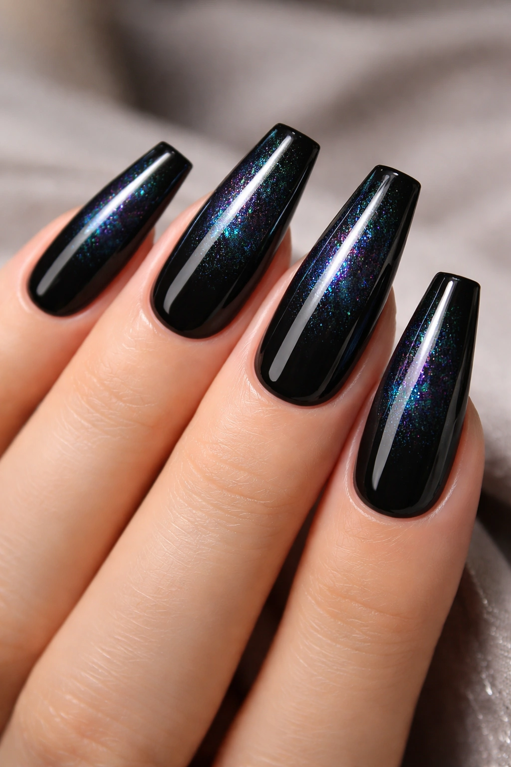 Close-up of coffin nails with glossy black base and iridescent shimmer top layer catching light