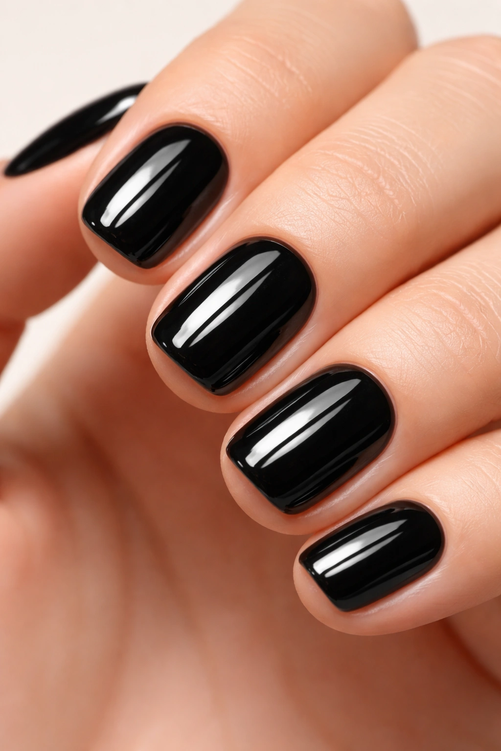 Close-up of short nails painted glossy black with high-shine finish
