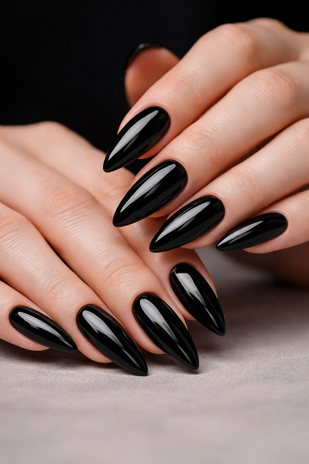 Close-up of glossy jet-black almond nails with high shine.
