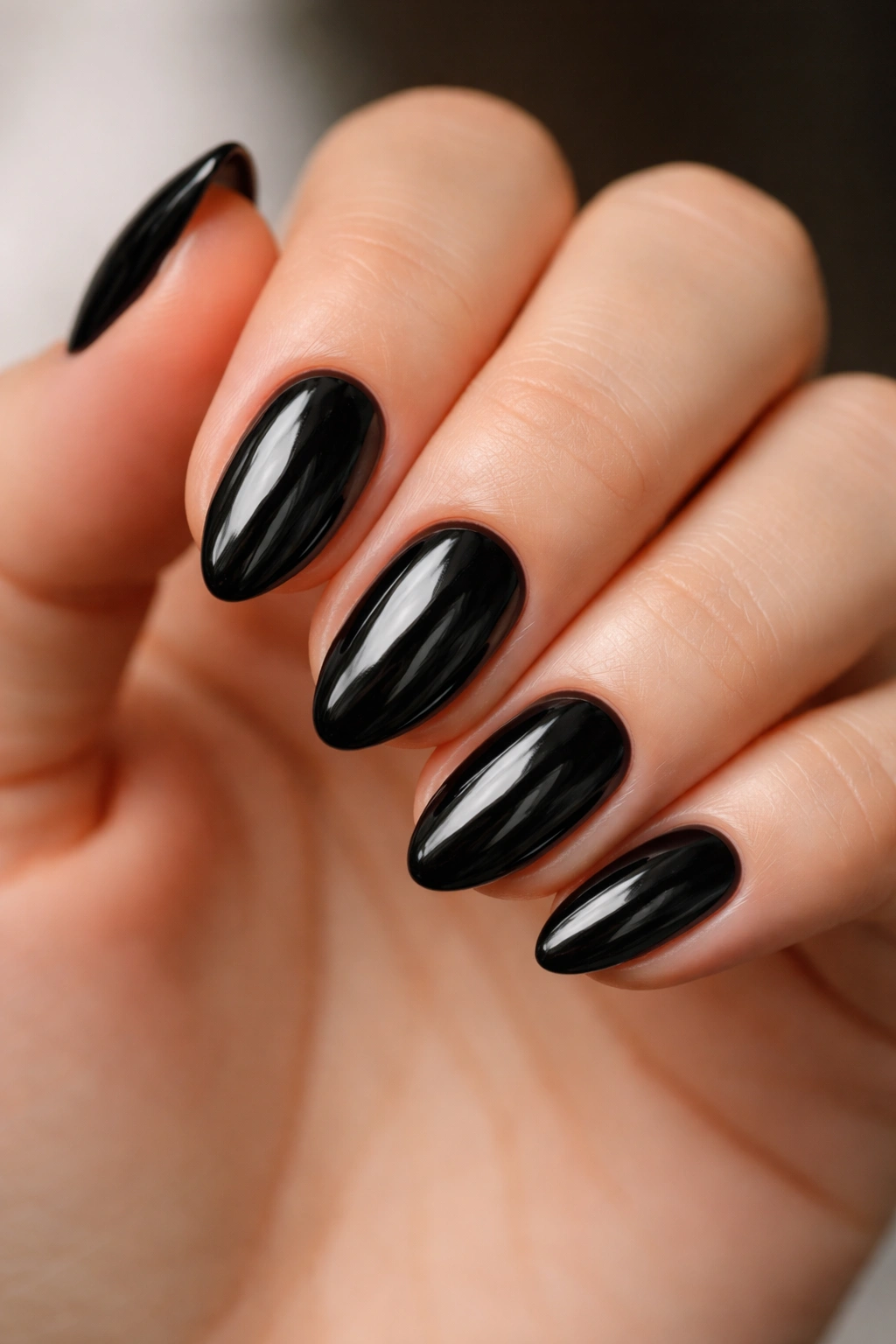 Close-up of glossy black almond nails on a clean hand