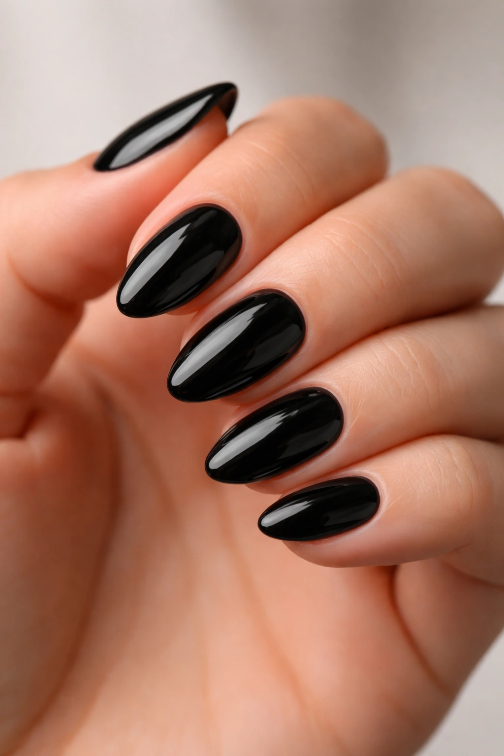 Close-up of very short almond nails in glossy black polish