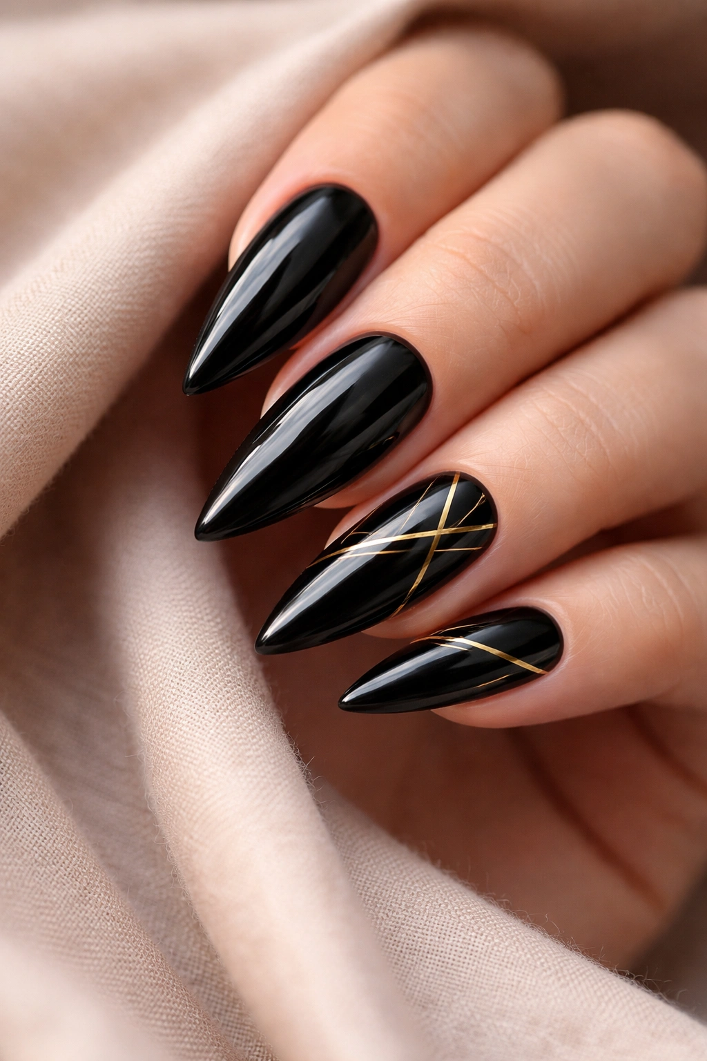 Close-up of glossy black stiletto nails with gold geometric accents on accent nails