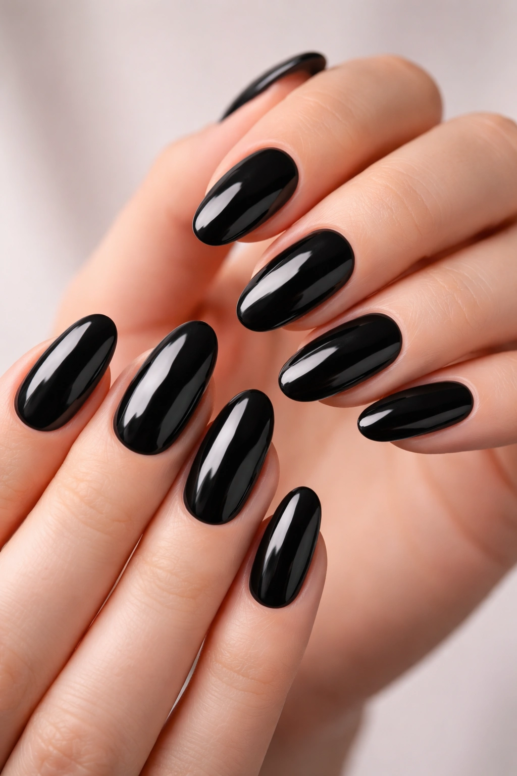 Close-up of glossy black oval nails on hands, high-shine manicure