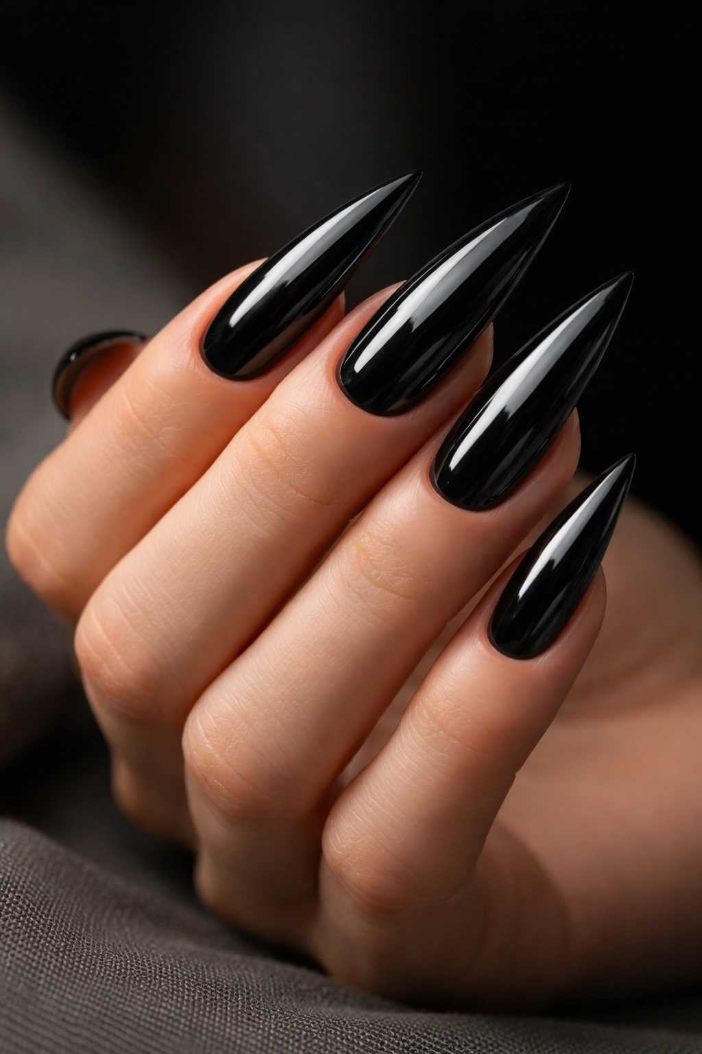 Close-up of long glossy black stiletto nails on a hand