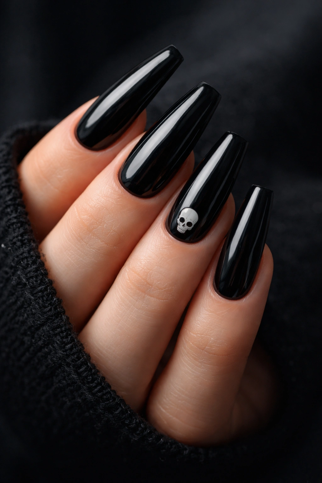 Glossy black coffin nails with a small white skull motif near the cuticle