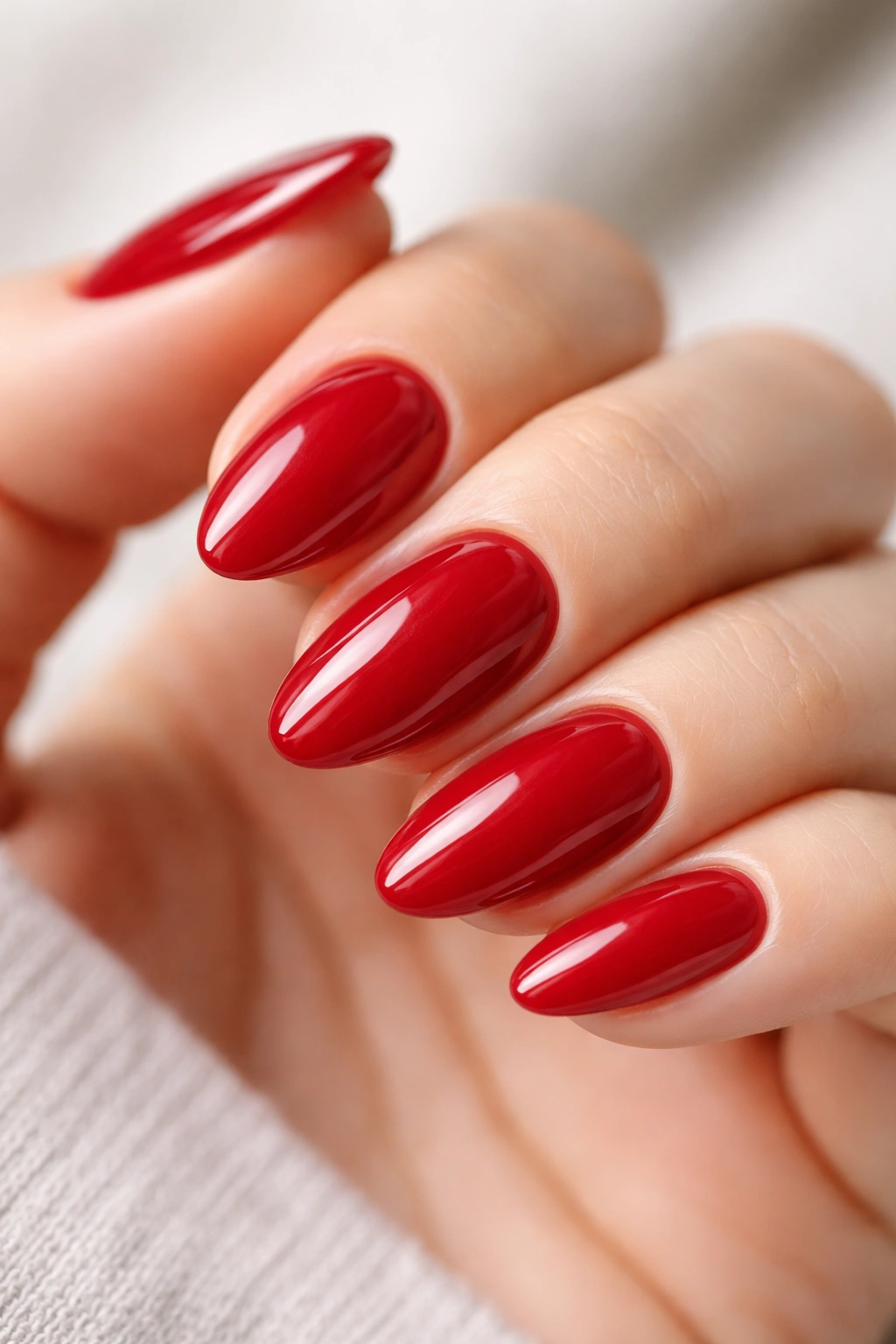Close-up of a short almond nail in glossy cherry red