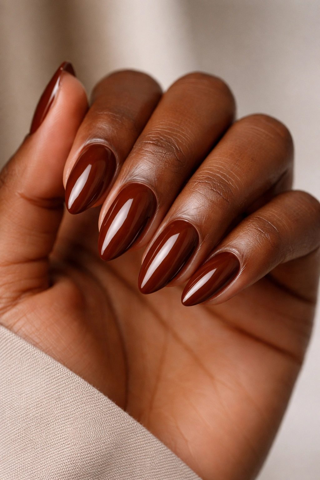 Close-up of glossy chestnut almond nails on a hand