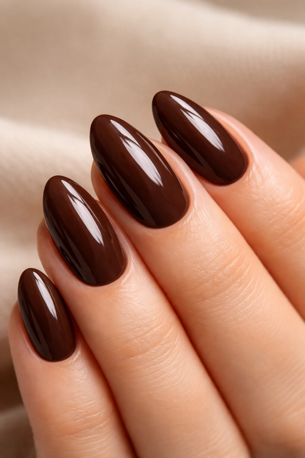Close-up of a short almond nail in glossy cocoa brown