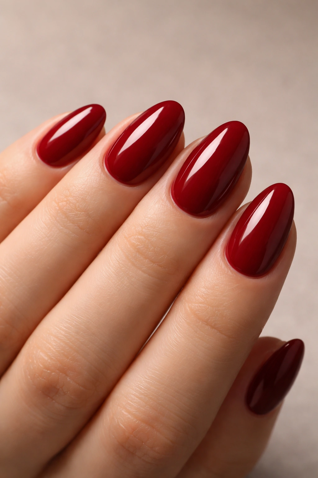 Close-up of glossy deep red short almond nails with neat edges