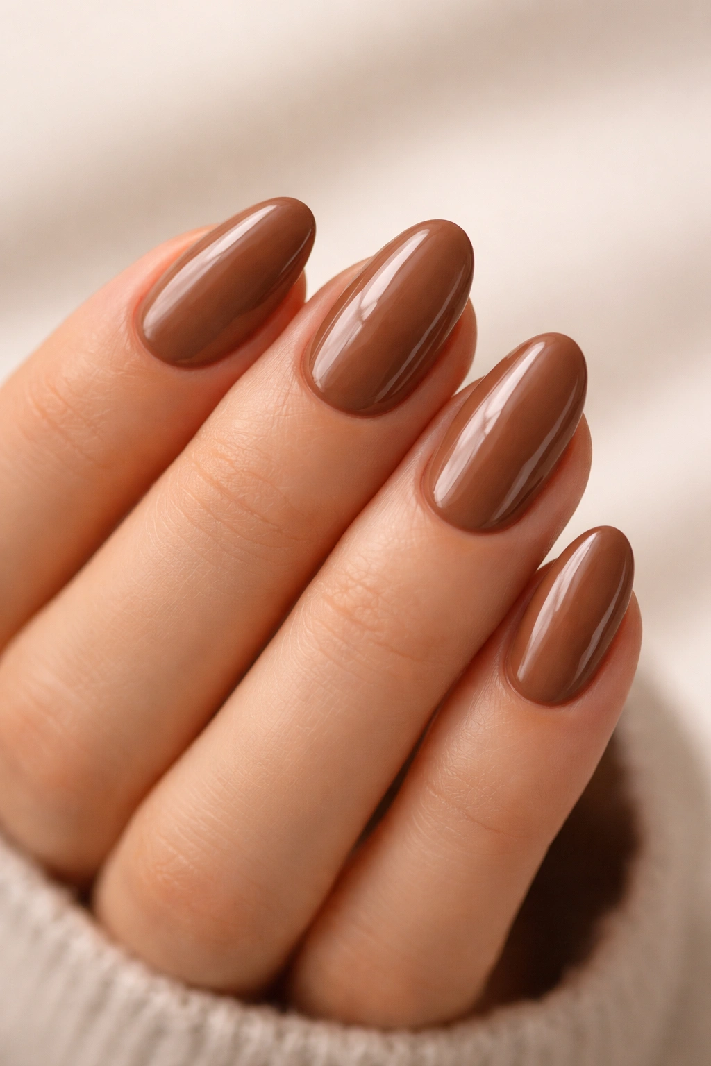 Short almond nails in hazelnut brown with glossy finish and rounded shape