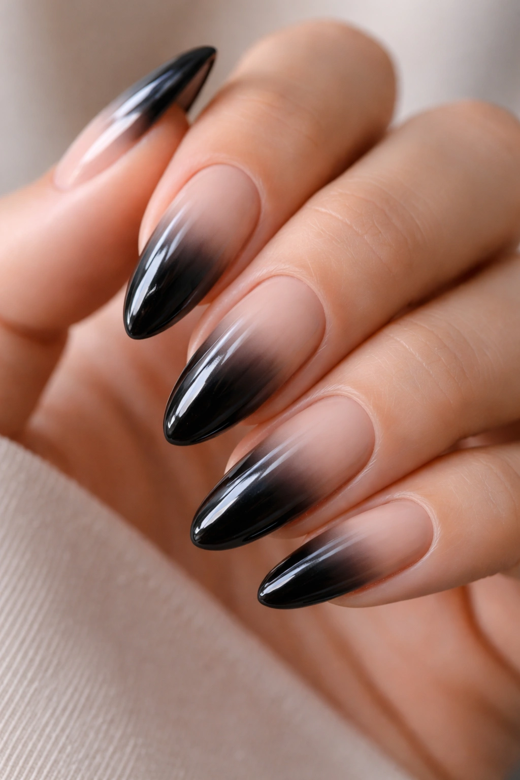 Close-up of almond nails with glossy black fade into nude cuticle